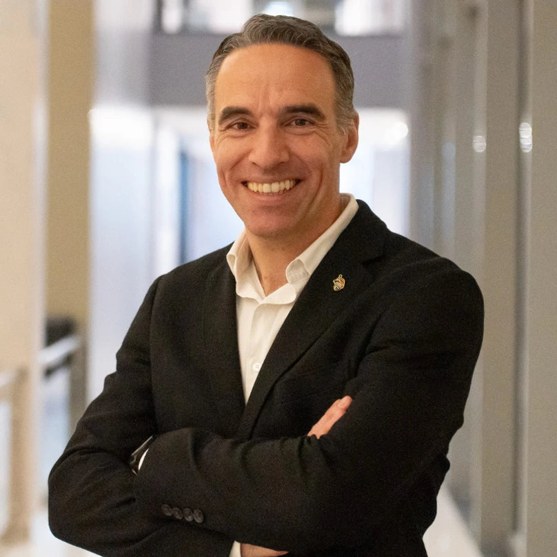 A professional portrait of Tiago, a member of the Loonawell Board of Directors and Business Unit Director at AstraZeneca Portugal. He is smiling with his arms crossed, wearing a dark blazer over a white shirt.